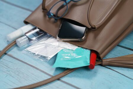 Hand bag with 2020 must have items smart phone, protective face mask, glasses and sanitizer gel corona virus or Covid-19 protection.の写真素材