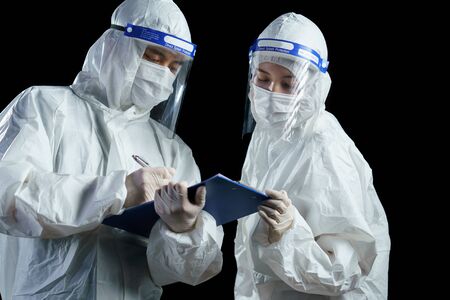 Doctor wearing PPE and face shield, looking for corona/covid-19 virus laboratory report.