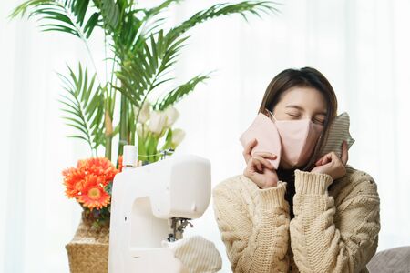 Woman sewing medical masks at home. Sewing on a sewing machineの写真素材