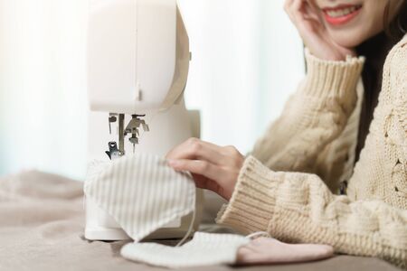 Woman using the sewing machine to sew the face mask during the coronavirus pandemia.