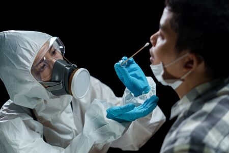 Woman doctor wearing hazmat suits  taking a nasal swab to test for possible coronavirus infection.