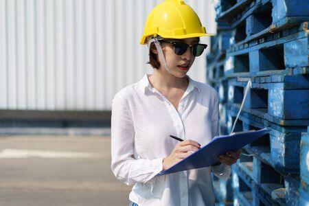 Woman engineer check building report, writing a technical report about the manufacturing process.