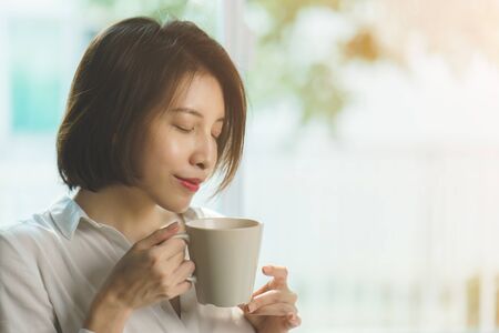 Woman hands holding hot cup of coffee or tea in morning sunlight.の写真素材
