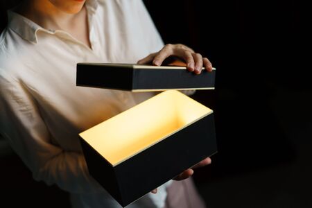 Woman opening a box with gold light mean something exciting inside.の写真素材