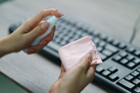Woman hand desinfecting devices at home for prevent disease by sanitazing keybord, corona virus or Covid-19 protection.の写真素材