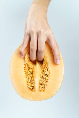 vagina symbol, hand with melon on white background. Concept masturbationの写真素材