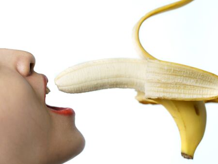 Side view of woman holding biting banana red lips on white background. isolatedの写真素材