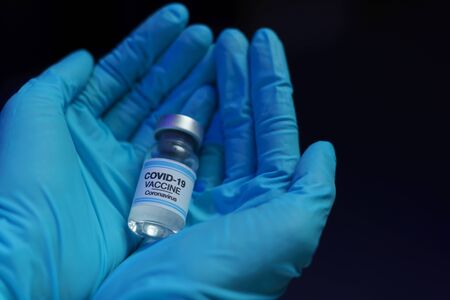 Hand in blue glove holding vaccine and syringe injection for prevention, immunization and treatment from corona virus infection.の写真素材