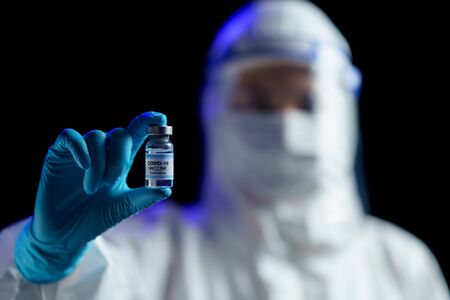 Woman in hazmat suit with vaccine for prevention, immunization and treatment from corona virus...