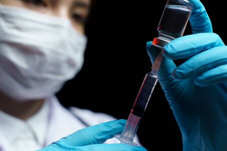 Doctor hand holding coronavirus vaccine shot for diseases outbreak vaccination, medicine and drug conceptの写真素材