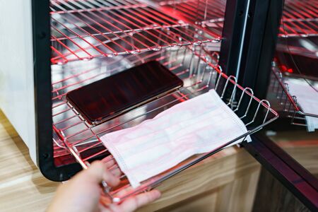 UV light sterilization of smartphone and face mask to Disinfection. COVID-19 prevention concept. ultra-violet Sterilization and Disinfection.の写真素材