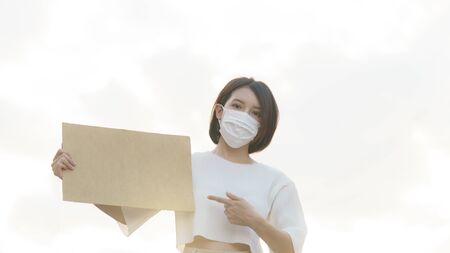 Woman wearing face mask holding a blank placard to put the text at protesting.の写真素材