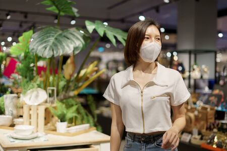Woman wearing face mask while walking at shopping mall for prevention from coronavirus, Covid-19.