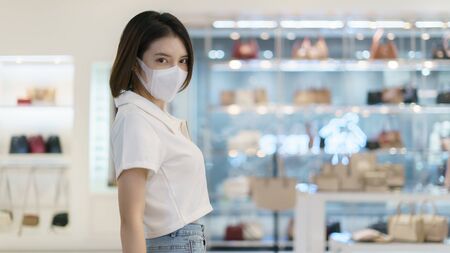 Woman wearing face mask while walking at shopping mall for prevention from coronavirus, Covid-19.の写真素材