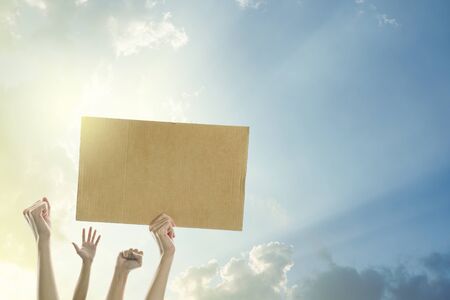 Woman's hands holding a blank banner to put the text at protesting with clear sky and sunlight background.の写真素材