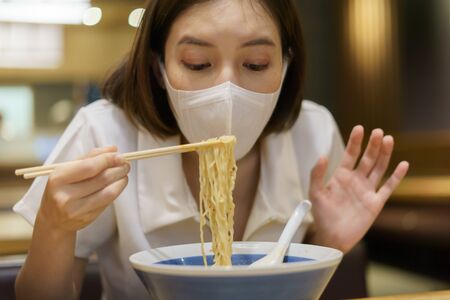 Woman wearing face mask trying to eat food, forgot during epidemic of the coronavirus and eating habits.の写真素材