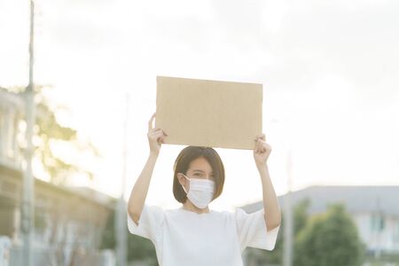 Woman wearing face mask holding a blank banner to put the text at protesting.の写真素材
