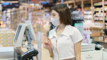 Women wearing face mask to prevent Coronavirus (Covid-19) and payment at cashier counter in supermarket.の写真素材