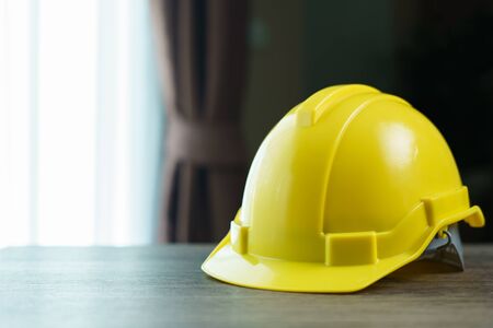 Yellow helmet, safety hat on brown wooden table.の写真素材