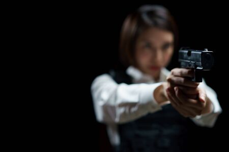 Woman wearing bulletproof vest shoots with gun at a target at indoor gun range.の写真素材
