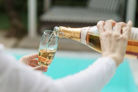 Woman Hand pouring champagne into a glass.