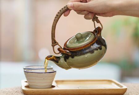 hot tea from pot into glass tea cup.の写真素材