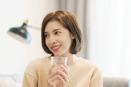 Woman holding transparent glass in her hand and drinking water.の写真素材