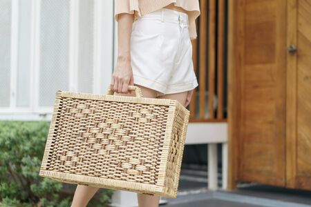 Close up of woman hand carries a wicker suitcase.の写真素材