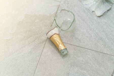 Broken champagne bottle on the floor.