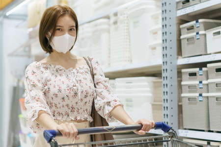 Asian woman wearing face mask push shopping cart in department store, during coronavirus or covid19 outbreak.の写真素材