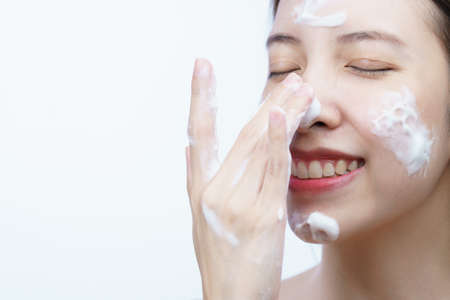 Asian woman wash her face with bubble cleansing foam isolated on white background.の写真素材