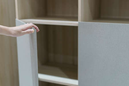 Female hand open the cupboard doors, open brown and white cabinet.の写真素材