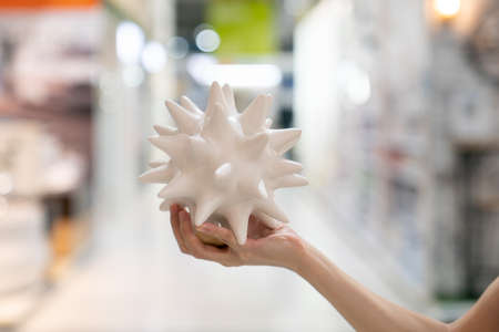 woman hand holding ceramic decoration look like coronavirus  in department store,  during coronavirus crisis or covid19 outbreak.の写真素材