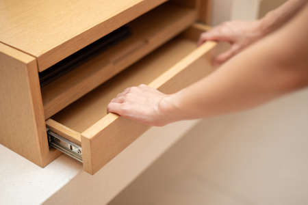 Woman hand pull open drawer wooden cabinet.の写真素材