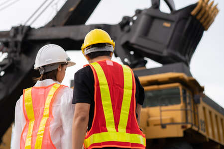 Back side of workers in lignite or coal mining with the truck transporting coal.