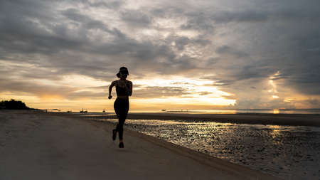 Woman jogging on beach in the morning.の写真素材