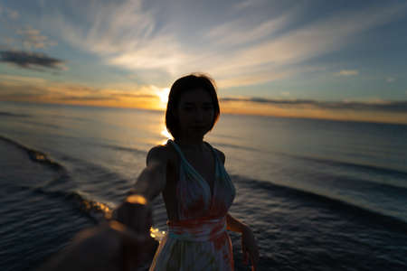 Woman and sunrise shot over the sea with beautiful cloud, sun disappeared behind a big cloud over...