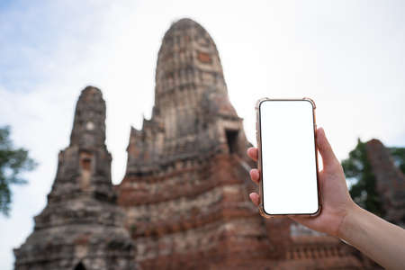 Mockup image of hand holding mobile phone with blank white screen with Pagoda.の写真素材