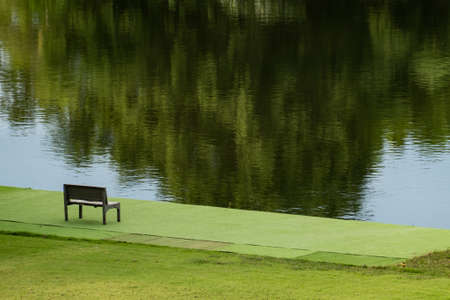 Wooden chair near river and green view.
