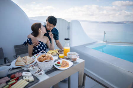 Couple tourist having breakfast on terrace hotel outdoor. Luxury and delicious food. Santorini, Greece.の写真素材