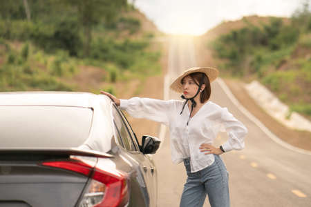 Woman standing with the car. pose with car in beautiful empty rural curve, asphalt road way.の写真素材