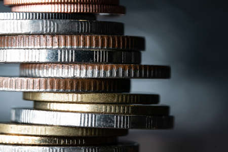 Close up of coins stacked with other in different positions on blurred background.の写真素材
