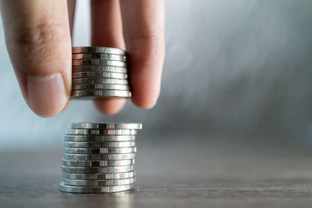 Hand put coins to stack of coins on white background, Investment and saving concept.