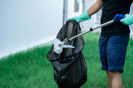 Man hand use garbage collector equipment keeping plastic waste into black bag at park.の写真素材