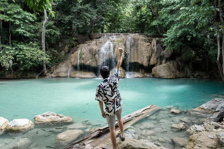 Man standing on the stone at Erawan waterfall at National Park, Kanchanaburi, Thailand.の写真素材