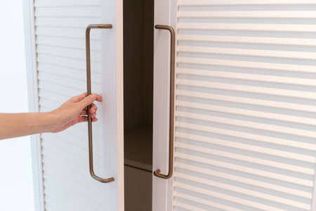 Closeup hand open wardrobe or wooden cupboard door.