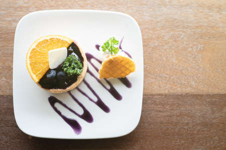 Blueberry tart on the table. Closeup of tartlets Served with fresh orange sliced.