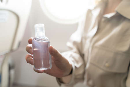 woman disinfects hands apply gel  alcohol, on board of an airplane. New Normal, safety and travel transportの写真素材