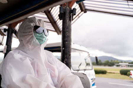 Person wearing protective suit , PPE with mask, sit on bus to entering airplane parking outside terminal in airport.の写真素材