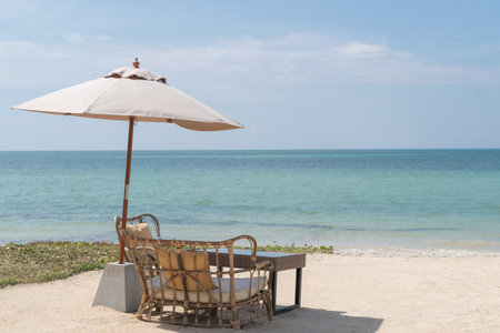 A Table with chairs and umbrella set up for a romantic meal on the beach, sky and sea in the background.の写真素材